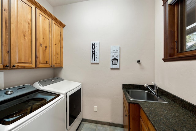 washroom featuring cabinet space, a sink, baseboards, and separate washer and dryer