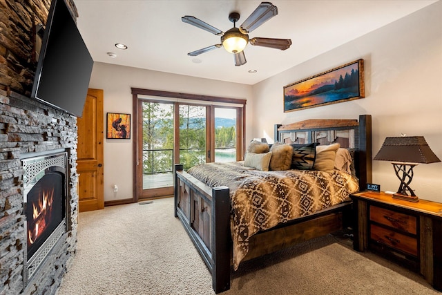 bedroom featuring light carpet, a fireplace, a ceiling fan, baseboards, and access to exterior