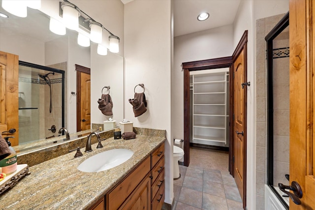 bathroom featuring a spacious closet, toilet, a stall shower, vanity, and tile patterned floors