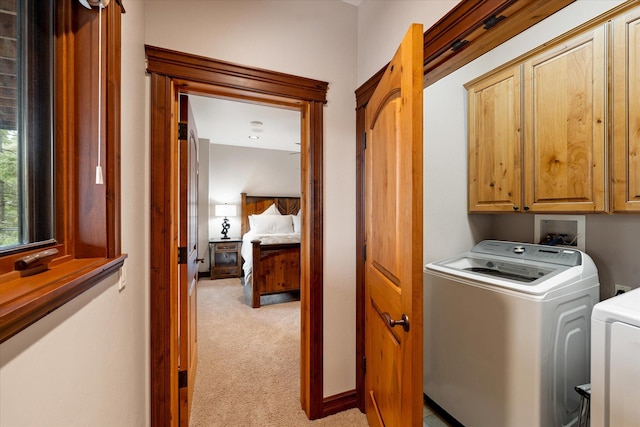 washroom featuring light carpet, independent washer and dryer, and cabinet space