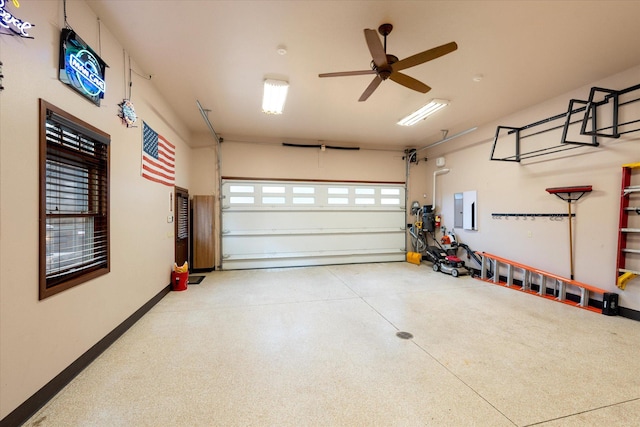 garage featuring ceiling fan, electric panel, and baseboards