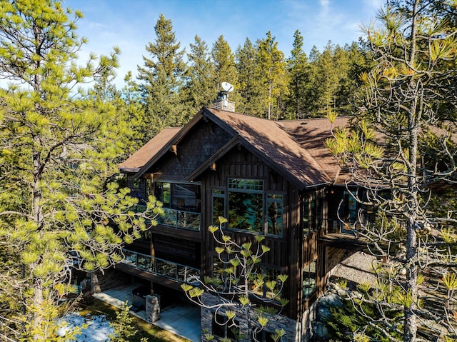 exterior space with roof with shingles and a chimney