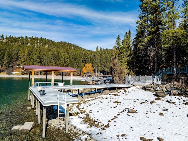 view of dock featuring a forest view and a water view