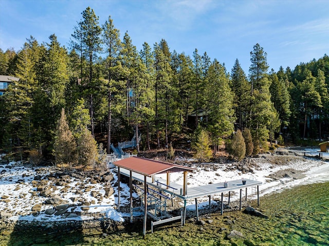 view of dock featuring boat lift and a wooded view