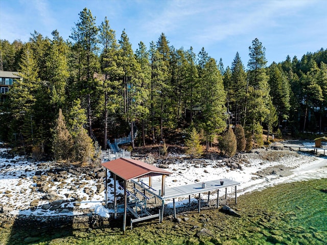 view of yard featuring a dock, boat lift, and a view of trees