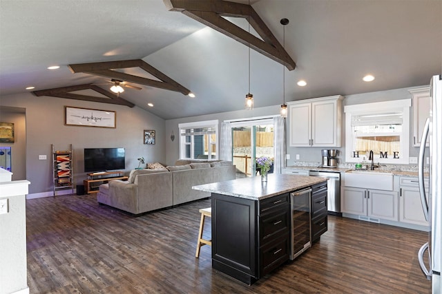 kitchen featuring a breakfast bar, appliances with stainless steel finishes, white cabinets, beverage cooler, and dark cabinetry