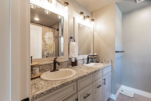 bathroom with double vanity, a sink, baseboards, and tile patterned floors