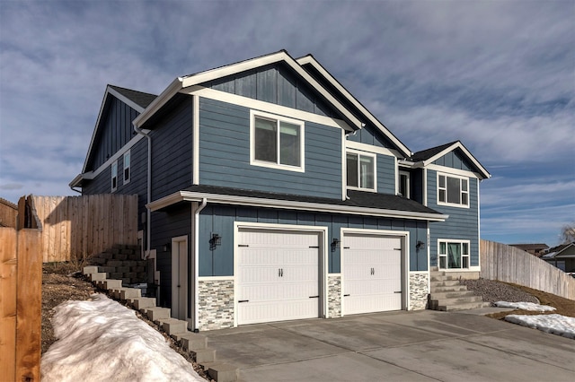 craftsman-style house with concrete driveway, board and batten siding, fence, a garage, and stone siding