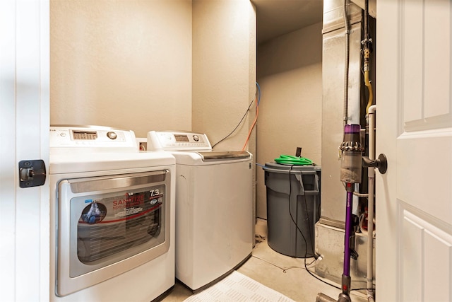 clothes washing area featuring laundry area, washing machine and dryer, and light tile patterned flooring