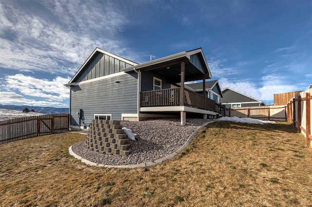 back of house featuring board and batten siding, a fenced backyard, and a lawn