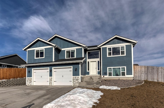 view of front of property featuring driveway, board and batten siding, an attached garage, and fence