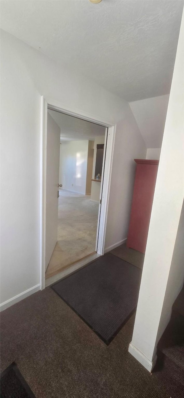 hall featuring lofted ceiling, carpet, and baseboards