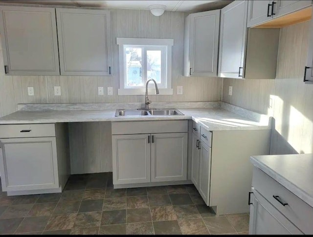 kitchen featuring light countertops, stone finish floor, and a sink