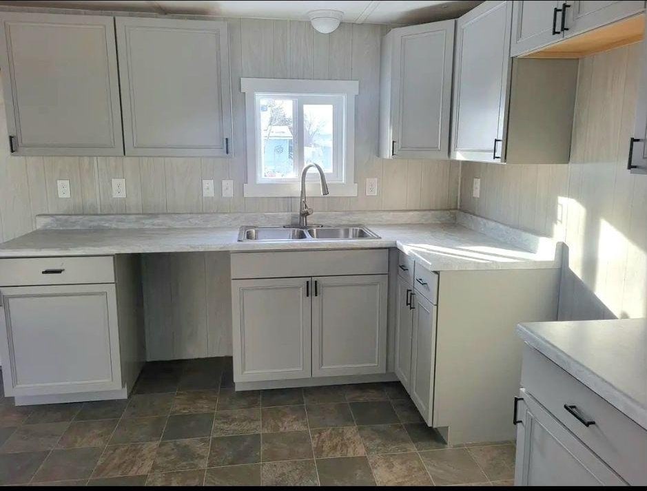 kitchen featuring stone finish flooring, light countertops, and a sink