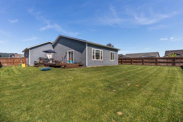 rear view of property featuring a fenced backyard, a deck, and a lawn