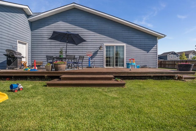 back of property featuring fence, a deck, and a yard