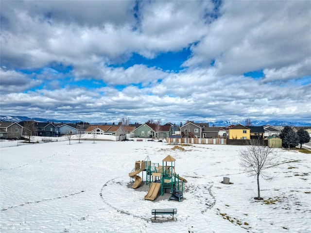 yard covered in snow featuring playground community, fence, and a residential view