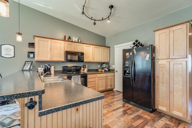 kitchen with lofted ceiling, a peninsula, black appliances, light brown cabinets, and a sink