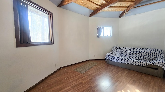 bedroom featuring lofted ceiling with beams, baseboards, and wood finished floors