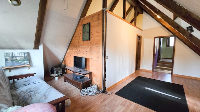 living area featuring beam ceiling, wood finished floors, high vaulted ceiling, baseboards, and stairs