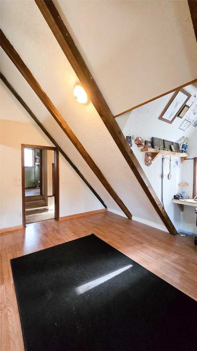 bonus room with lofted ceiling with skylight, baseboards, and wood finished floors