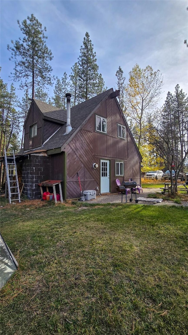 back of property with a lawn and roof with shingles