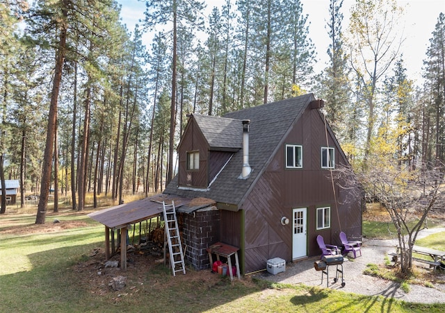 view of property exterior featuring gravel driveway, a yard, a barn, and roof with shingles