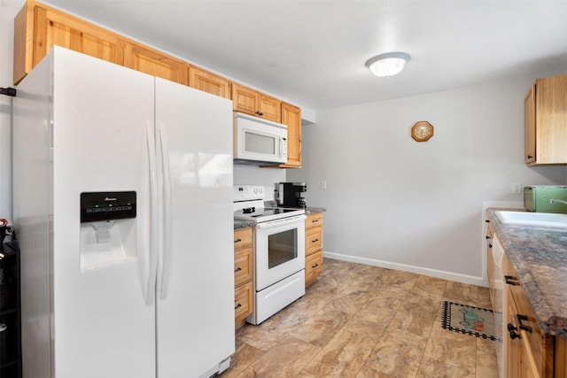 kitchen with white appliances, dark countertops, a sink, and baseboards