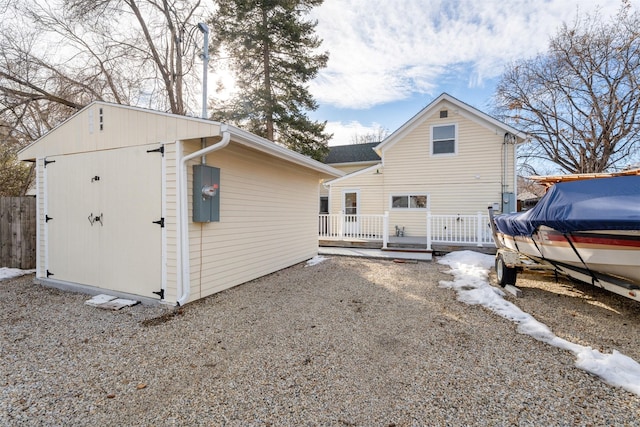 rear view of property featuring an outbuilding, fence, and a deck