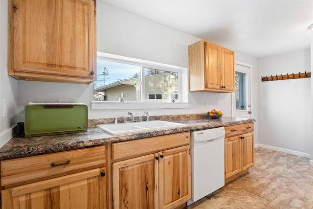 kitchen featuring white dishwasher, a sink, and baseboards