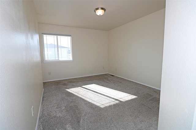 spare room featuring carpet flooring and baseboards