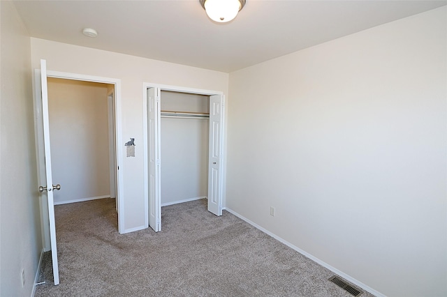 unfurnished bedroom featuring a closet, carpet flooring, visible vents, and baseboards