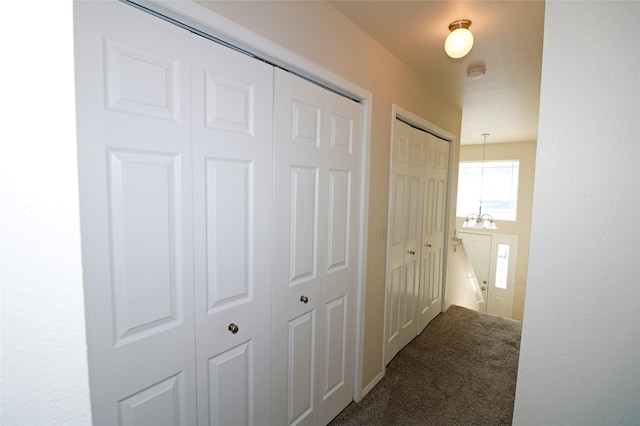 corridor with carpet floors and a chandelier