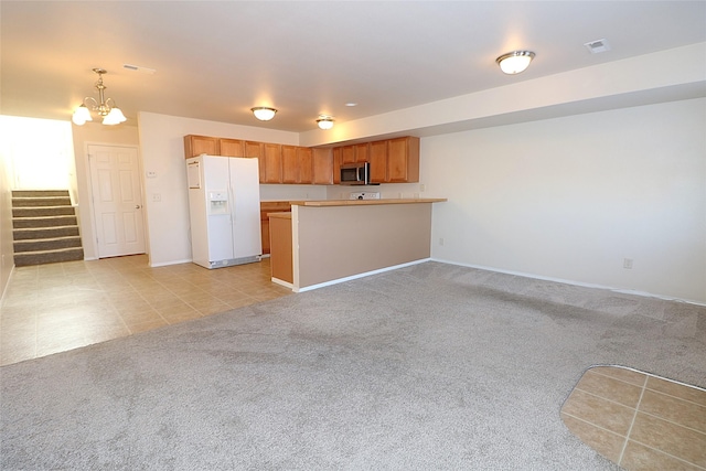 kitchen featuring white refrigerator with ice dispenser, a notable chandelier, stainless steel microwave, open floor plan, and light carpet