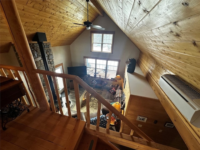 interior space with vaulted ceiling with beams, ceiling fan, wooden ceiling, wood finished floors, and a wood stove