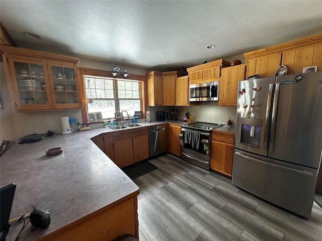 kitchen with stainless steel appliances, light countertops, a sink, and tasteful backsplash