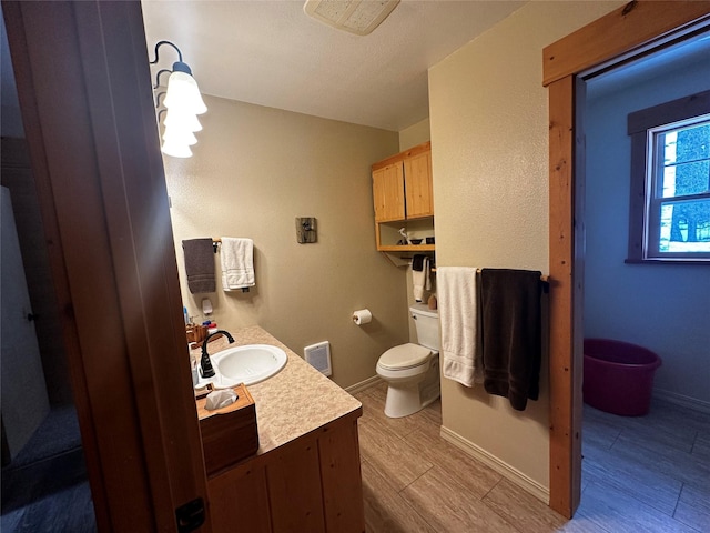 bathroom featuring baseboards, vanity, toilet, and wood finished floors