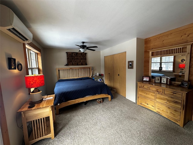 bedroom with wooden walls, a ceiling fan, a wall unit AC, carpet, and a closet