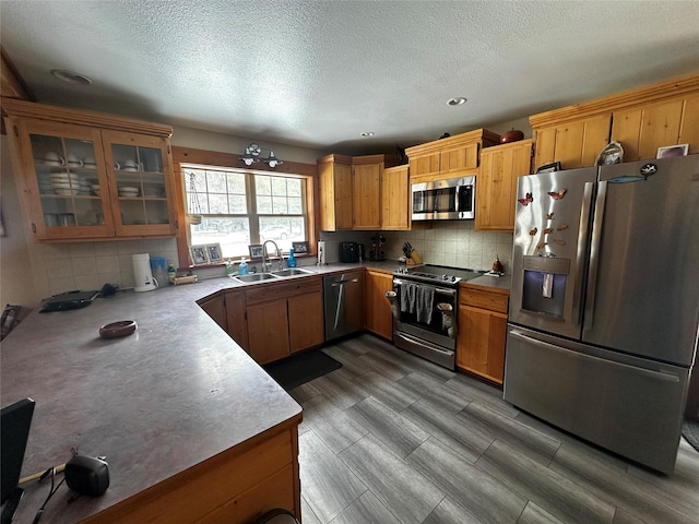 22 Pinewoods Dr, Trout Creek, MT 59874 - kitchen with appliances with stainless steel finishes, a sink, tasteful backsplash, a textured ceiling, and glass insert cabinets