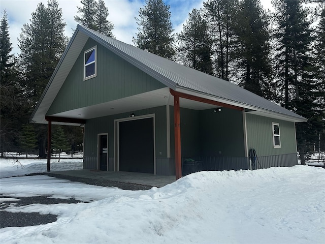 snow covered garage with a carport