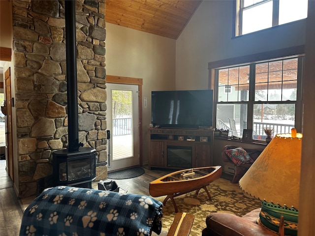 living area with high vaulted ceiling, wood ceiling, a wood stove, and wood finished floors