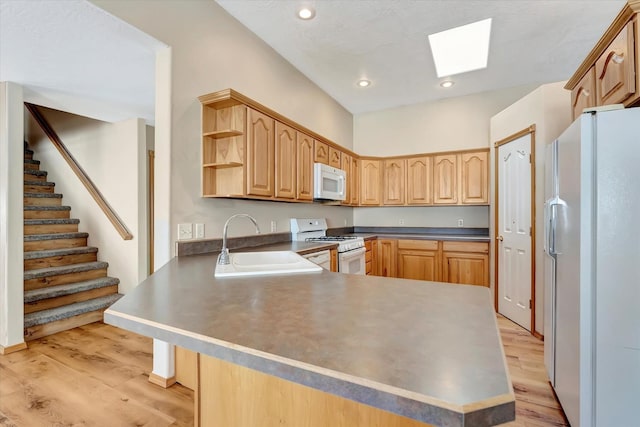 6864 Joy Dr, Missoula, MT 59803 - kitchen with white appliances, a sink, a skylight, a peninsula, and light wood finished floors