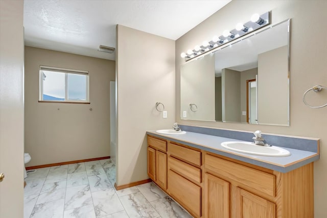 6864 Joy Dr, Missoula, MT 59803 - bathroom with marble finish floors, toilet, double vanity, and baseboards