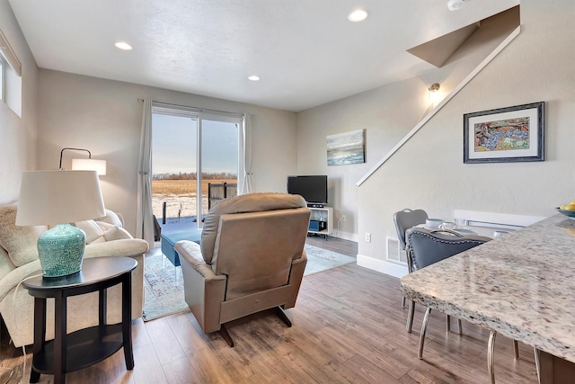 living room featuring recessed lighting, visible vents, baseboards, and wood finished floors