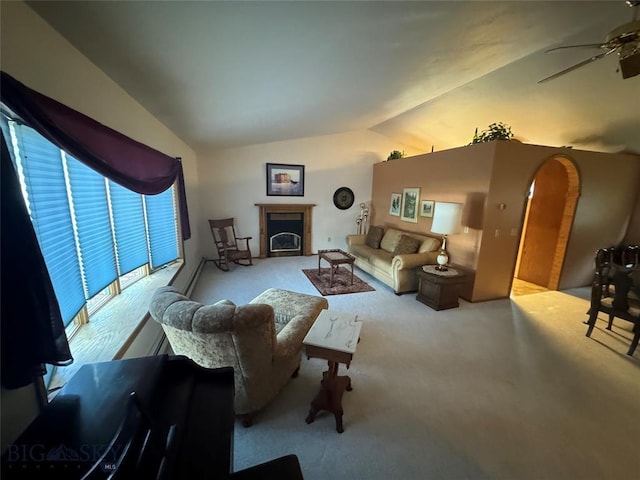 living room featuring a fireplace with flush hearth, vaulted ceiling, and a ceiling fan