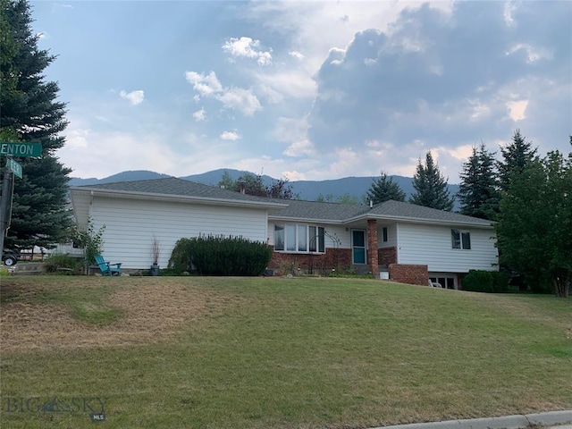 ranch-style home featuring brick siding, a mountain view, and a front lawn