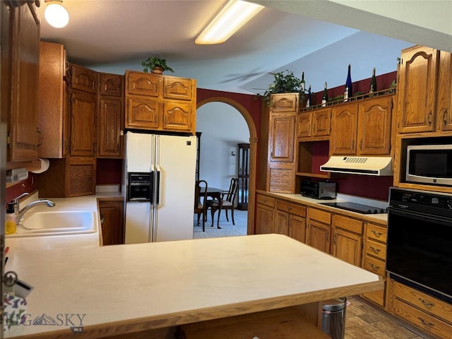 kitchen with black appliances, arched walkways, extractor fan, and light countertops