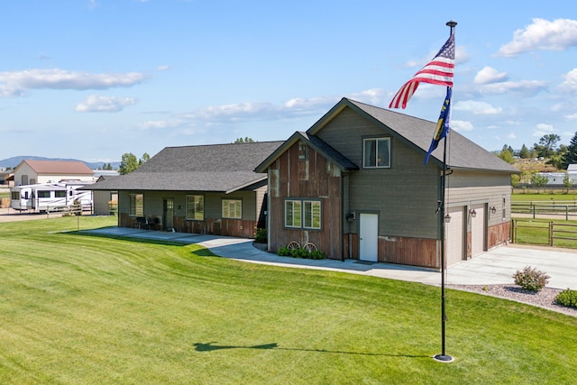 rear view of property with a garage, concrete driveway, a lawn, and fence