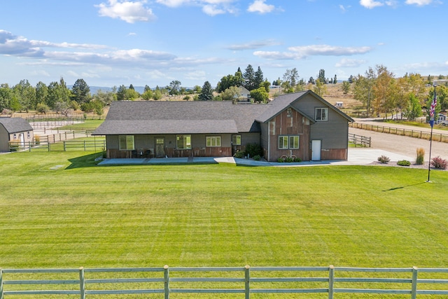 view of front facade with a shingled roof, a front yard, and fence