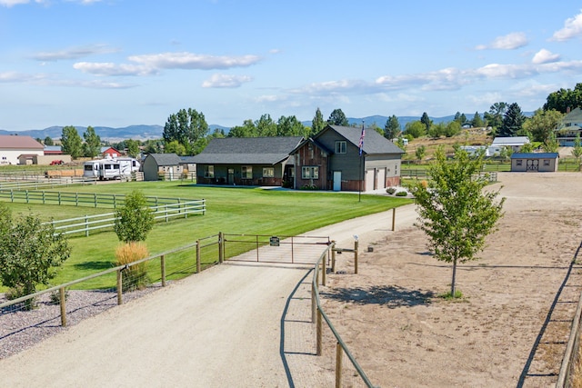 view of community with a rural view, driveway, a lawn, and a mountain view